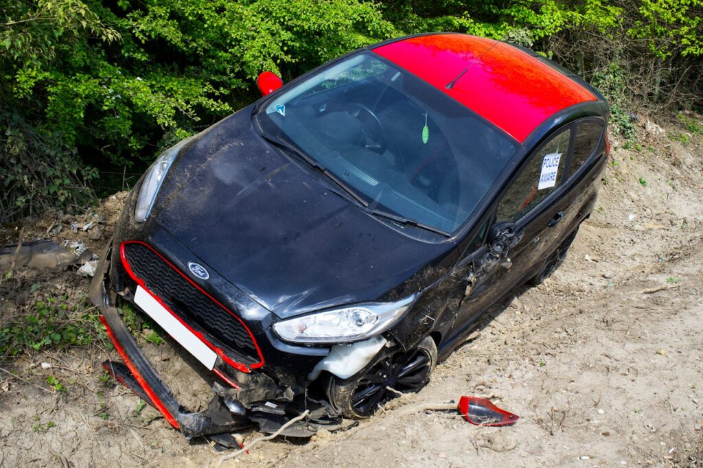 A black and red Ford Fiesta lies abandoned and damaged off-road in Welwyn Garden City, UK.